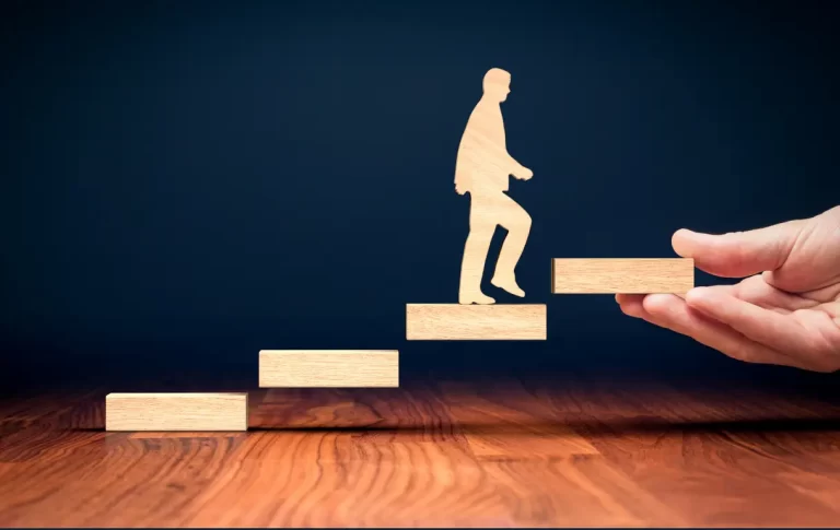 a hand holding a wooden block with a person walking up the stairs