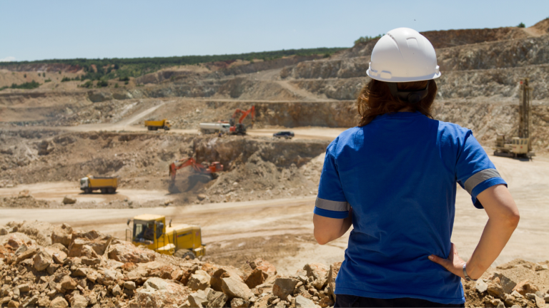 Women in hard hat looking out over mining operations