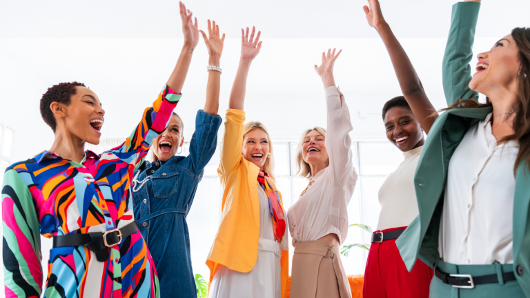 diverse women in leadership training with their arms raised in a cheer